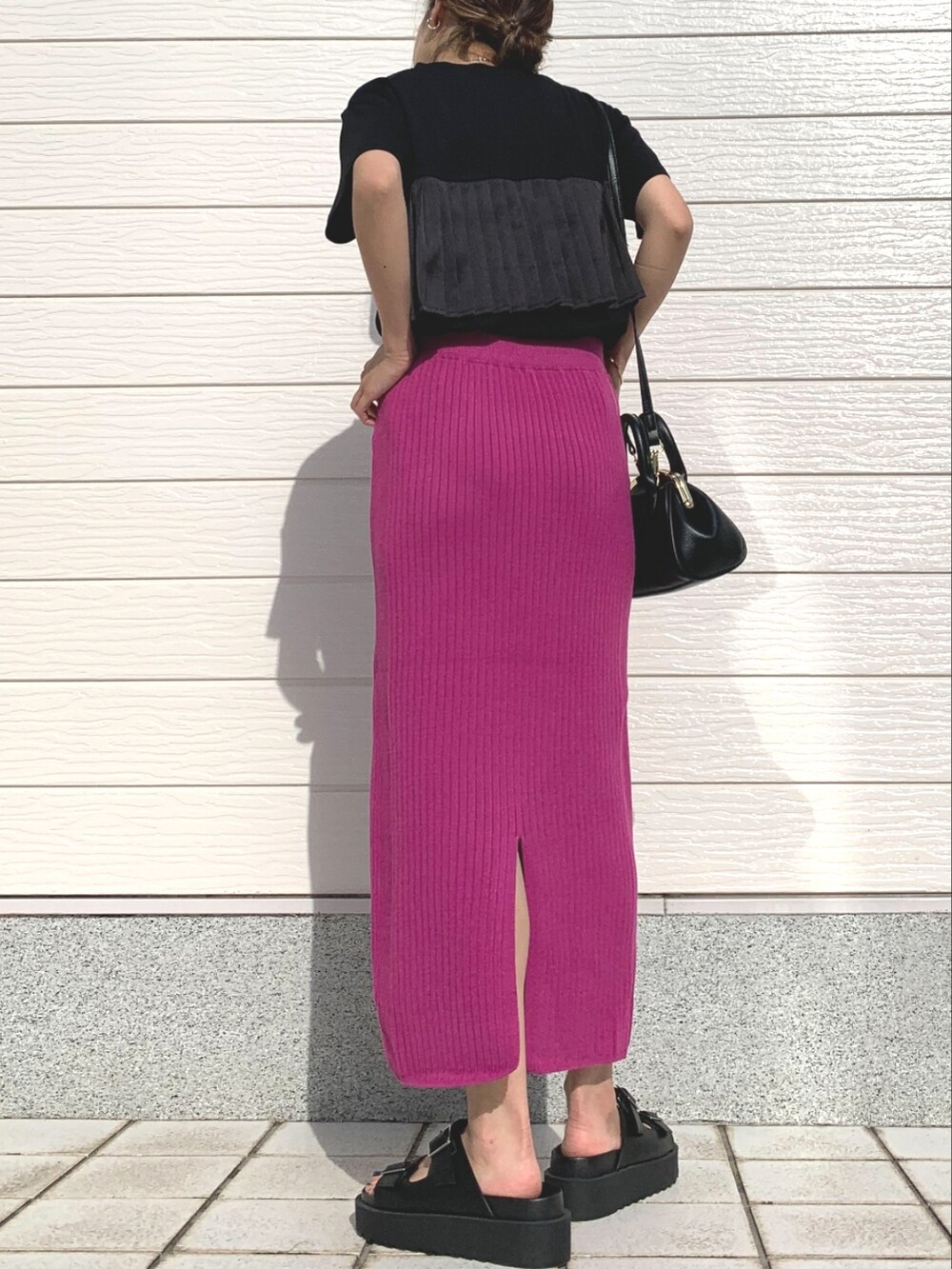 ブラック系のTシャツ/カットソー、ピンク系のスカート、ブラック系のサンダルを着用したレディースの春コーディネートの2枚目の写真