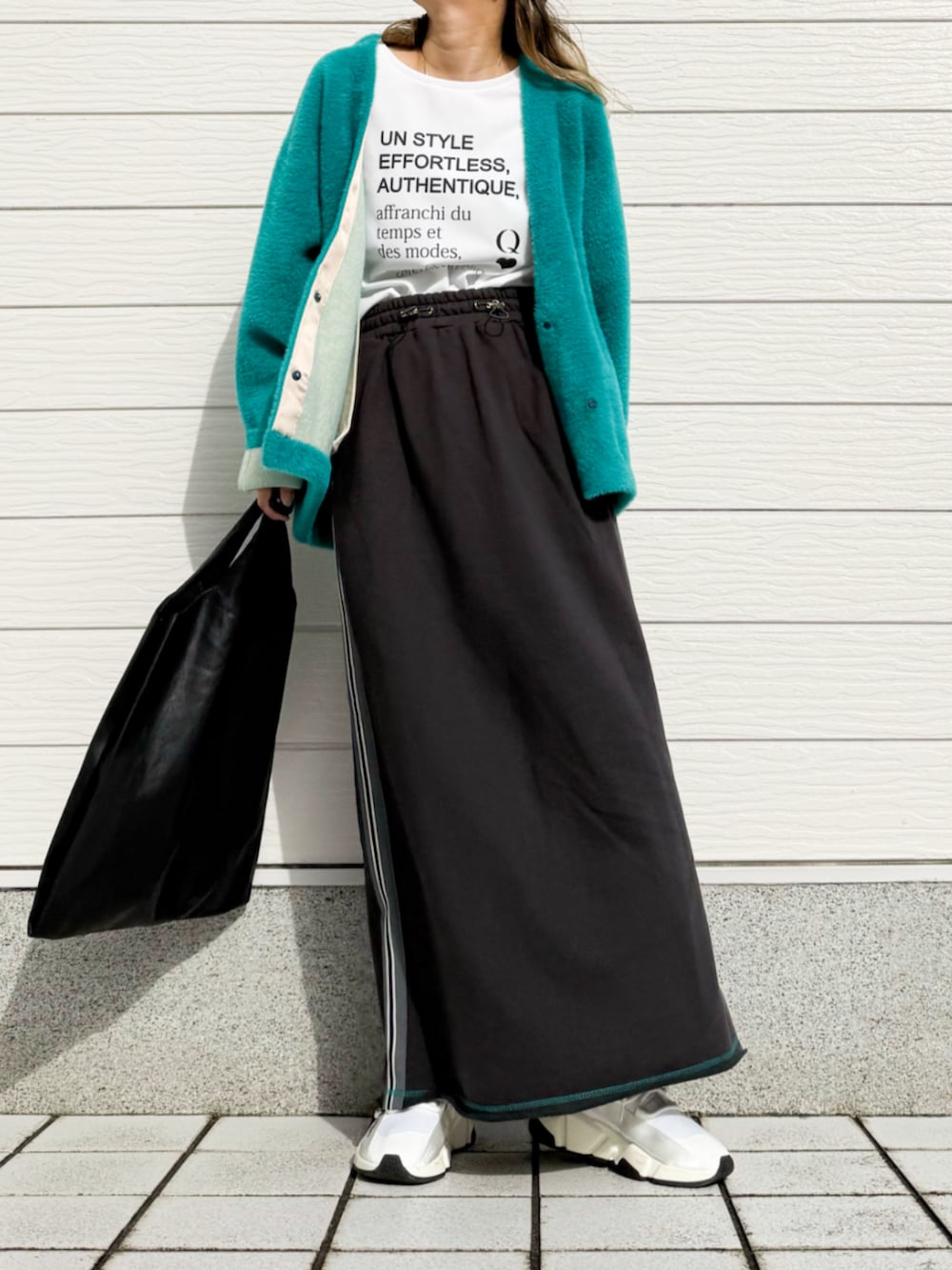 グレー系のスカート、ホワイト系のTシャツ/カットソー、グリーン系のカーディガン/ボレロを着用したレディースの秋コーディネートの2枚目の写真