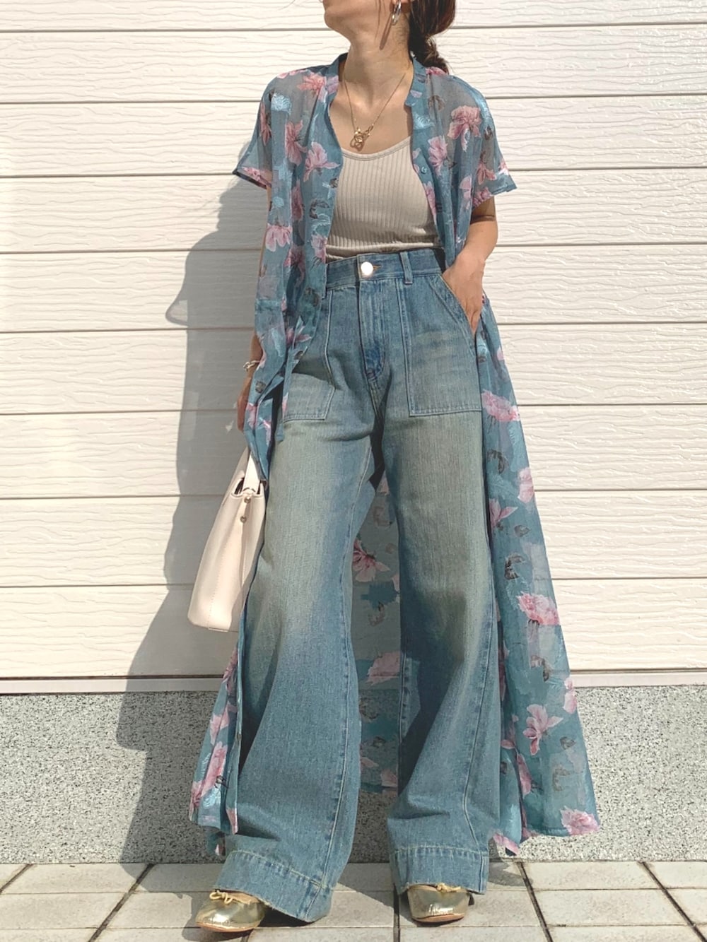 ブルー系のデニムパンツ、ベージュ系のキャミソール、ホワイト系のハンドバッグを着用したレディースの春コーディネートの2枚目の写真