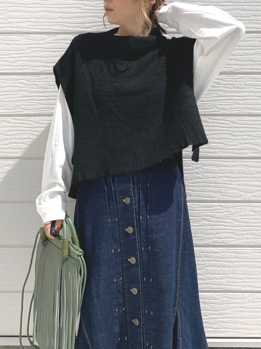 ブルー系のデニムスカート、ブラック系のスニーカー、ブラック系のベストを着用したレディースの秋コーディネートの3枚目の写真