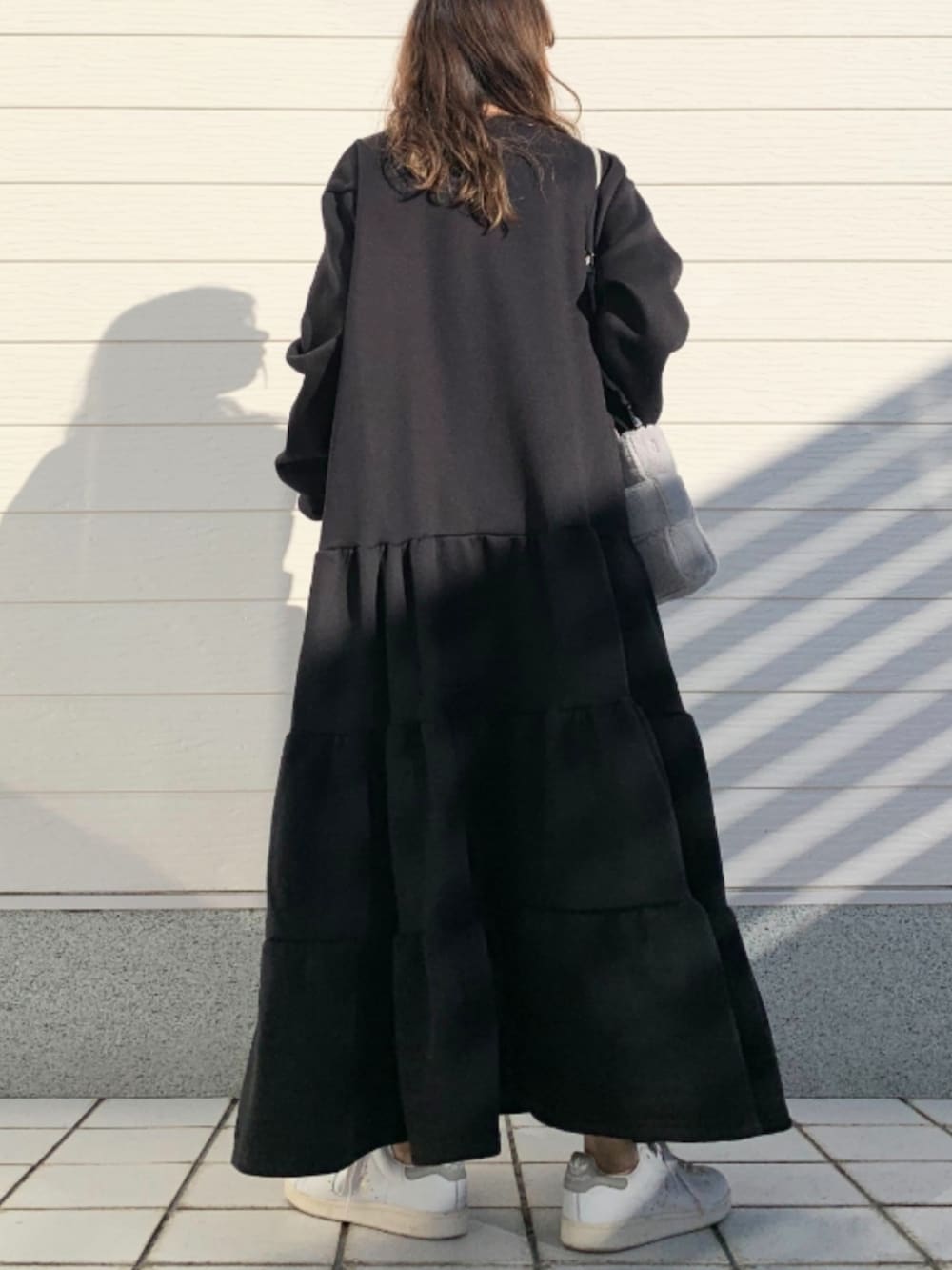 グレー系のショルダーバッグ、ホワイト系のスニーカー、ブラック系のワンピースを着用したレディースの冬コーディネートの4枚目の写真