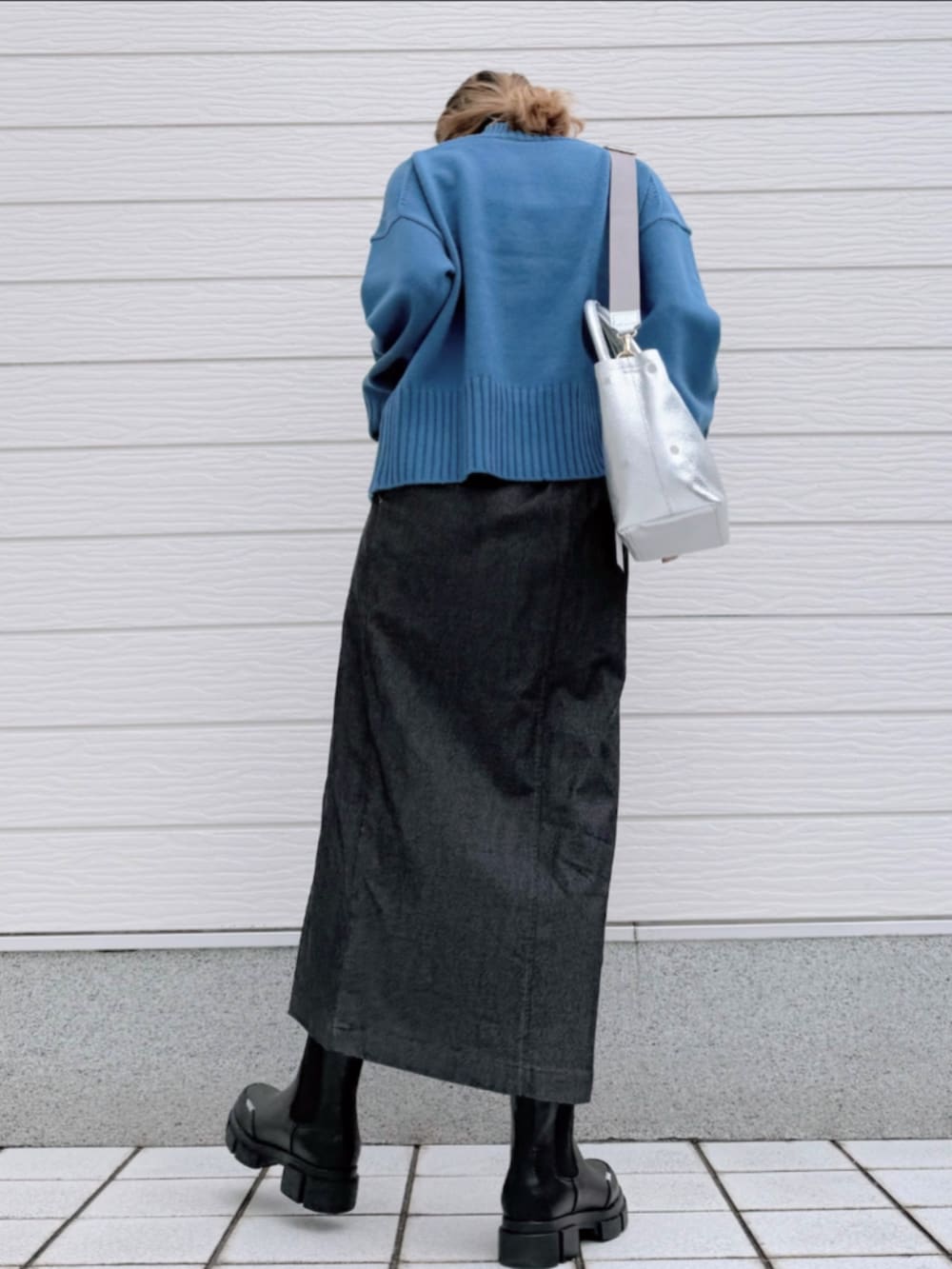 グレー系のスカート、ブラック系のブーツ、シルバー系のトートバッグを着用したレディースの冬コーディネートの3枚目の写真