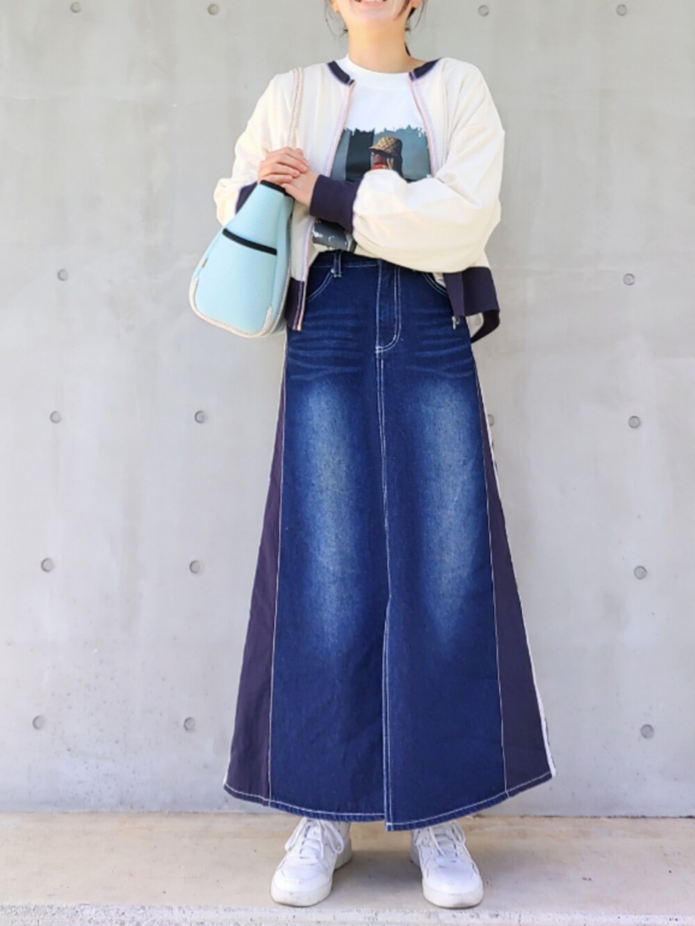 ブルー系のトートバッグ、ブルー系のデニムスカート、ホワイト系のスニーカーを着用したレディースの冬コーディネートの2枚目の写真