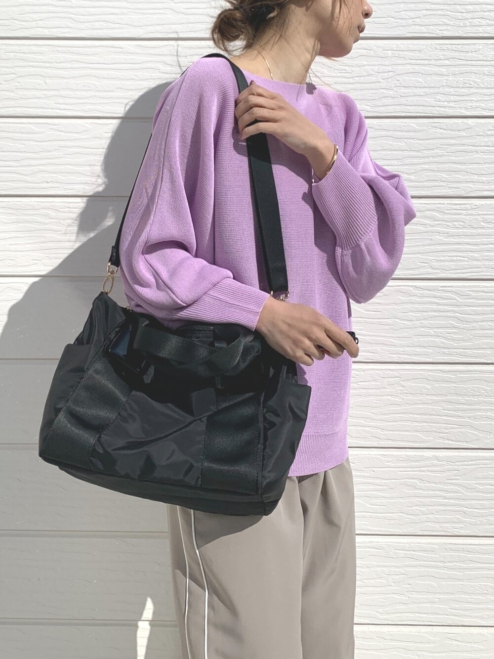 ブラック系のトートバッグ、ベージュ系のその他パンツ、パープル系のニット/セーターを着用したレディースの春コーディネートの3枚目の写真