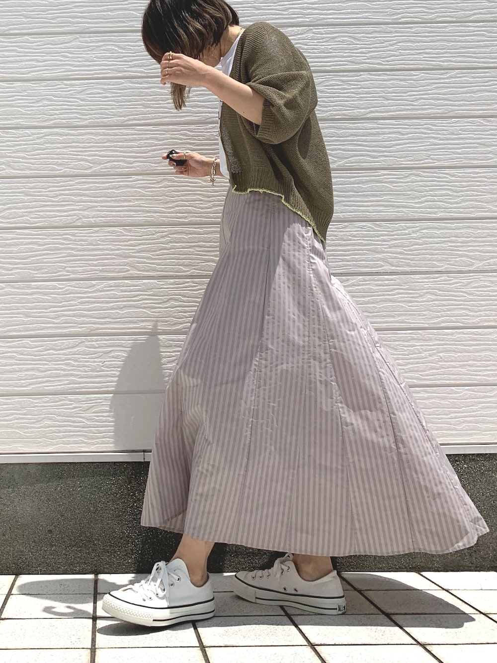 ホワイト系のスニーカー、ベージュ系のスカート、ホワイト系のTシャツ/カットソーを着用したレディースの春コーディネートの2枚目の写真