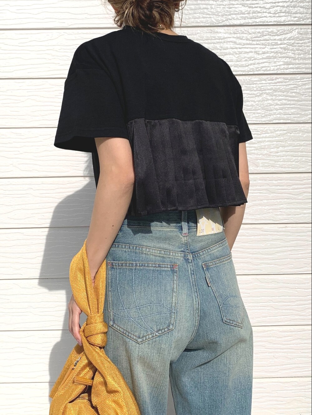 ブルー系のデニムパンツ、ブラック系のサンダル、イエロー系のショルダーバッグを着用したレディースの春コーディネートの3枚目の写真