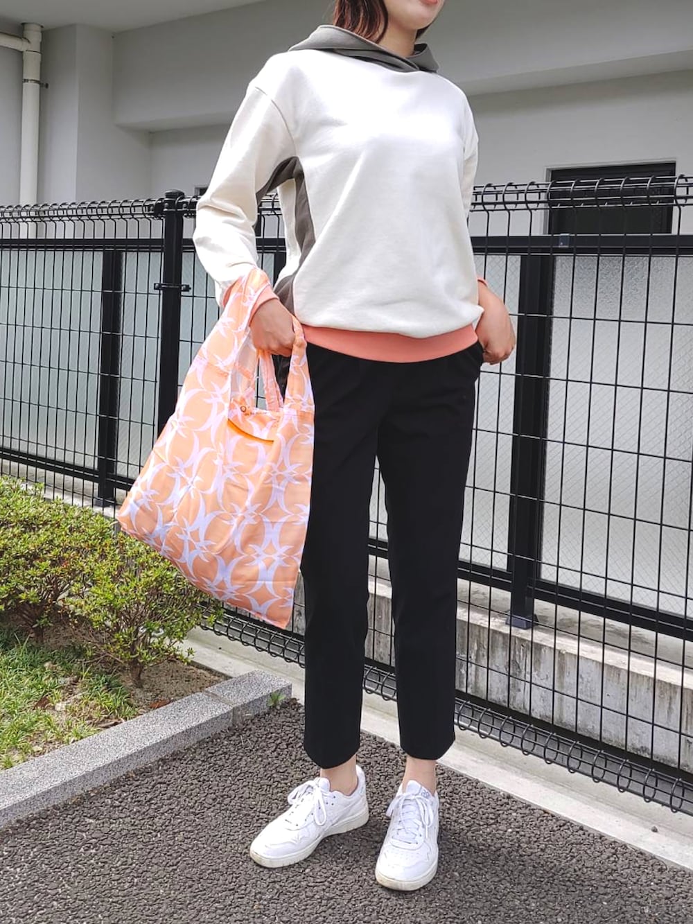 オレンジ系のエコバッグ/サブバッグ、ホワイト系のパーカー、ホワイト系のスニーカーを着用したレディースの秋コーディネートの3枚目の写真