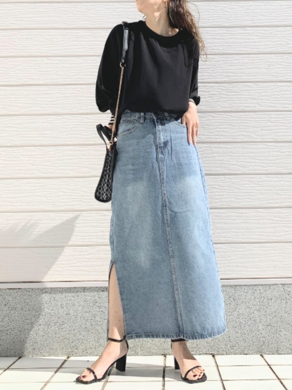 ブルー系のデニムスカート、ブラック系のシャツ/ブラウス、ブラック系のショルダーバッグを着用したレディースの春コーディネートの2枚目の写真