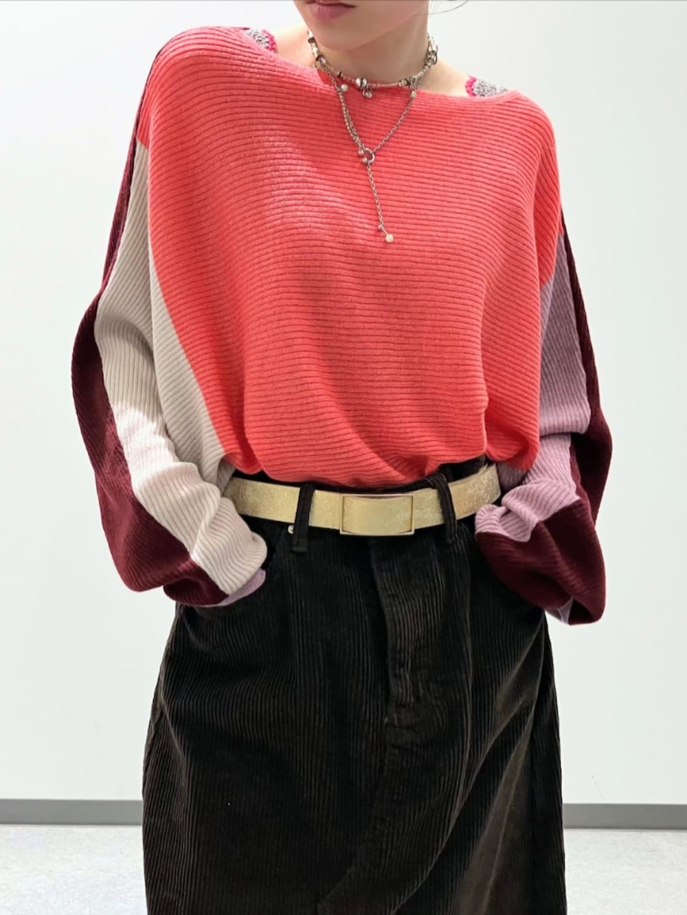 レッド系のニット/セーター、ブラウン系のスカート、ベージュ系のトートバッグを着用したレディースの秋コーディネートの5枚目の写真