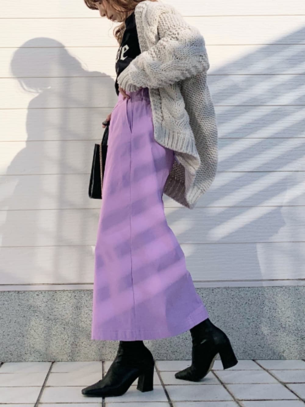 パープル系のスカート、ブラック系のショルダーバッグ、グレー系のカーディガン/ボレロを着用したレディースの秋コーディネートの2枚目の写真