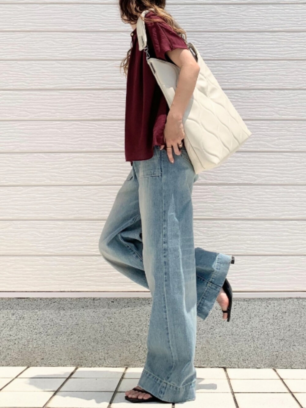 ブルー系のデニムパンツ、レッド系のシャツ/ブラウス、ホワイト系のハンドバッグを着用したレディースの夏コーディネートの2枚目の写真