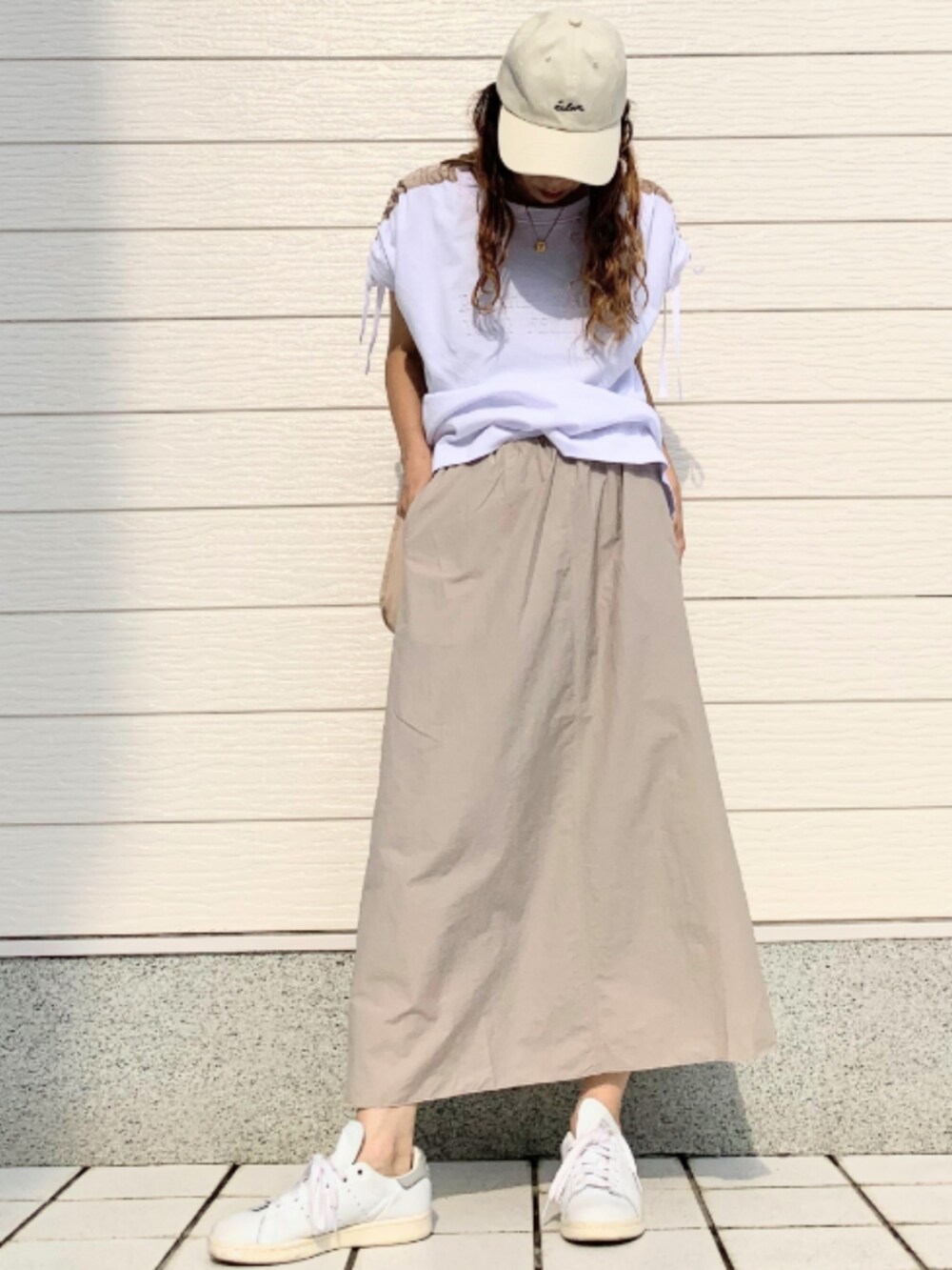 ホワイト系のスニーカー、ホワイト系のTシャツ/カットソー、ベージュ系のスカートを着用したレディースの夏コーディネートの3枚目の写真