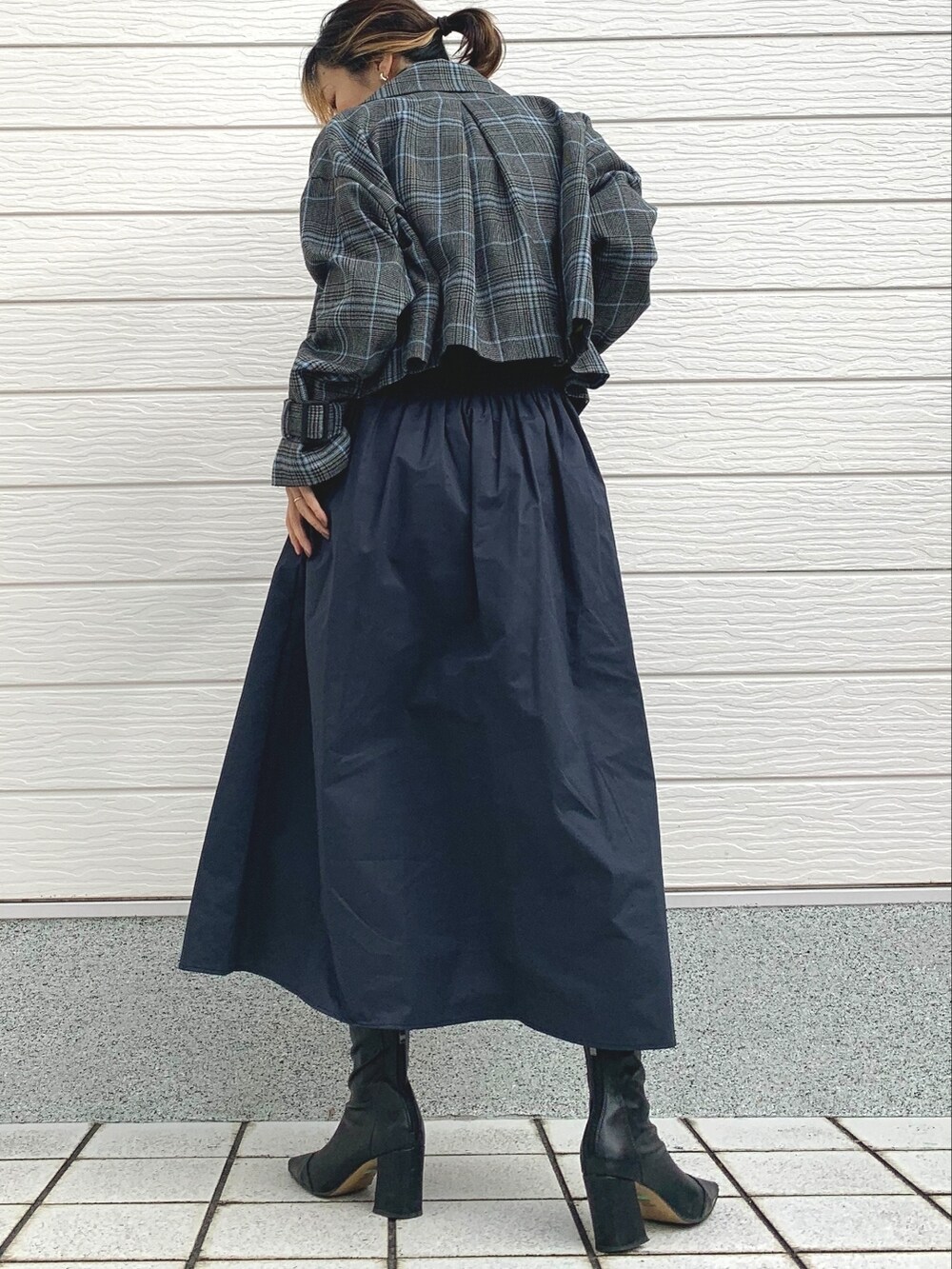 ブルー系のスカート、グレー系のニット/セーター、グレー系のトレンチコートを着用したレディースの冬コーディネートの2枚目の写真