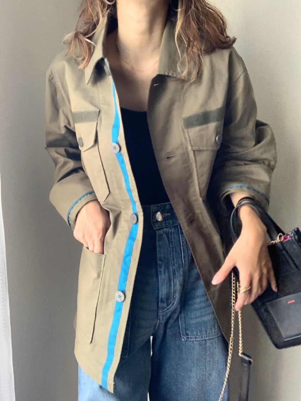 ブルー系のデニムパンツ、グリーン系のミリタリージャケット、ブラック系のショルダーバッグを着用したレディースの秋コーディネートの3枚目の写真