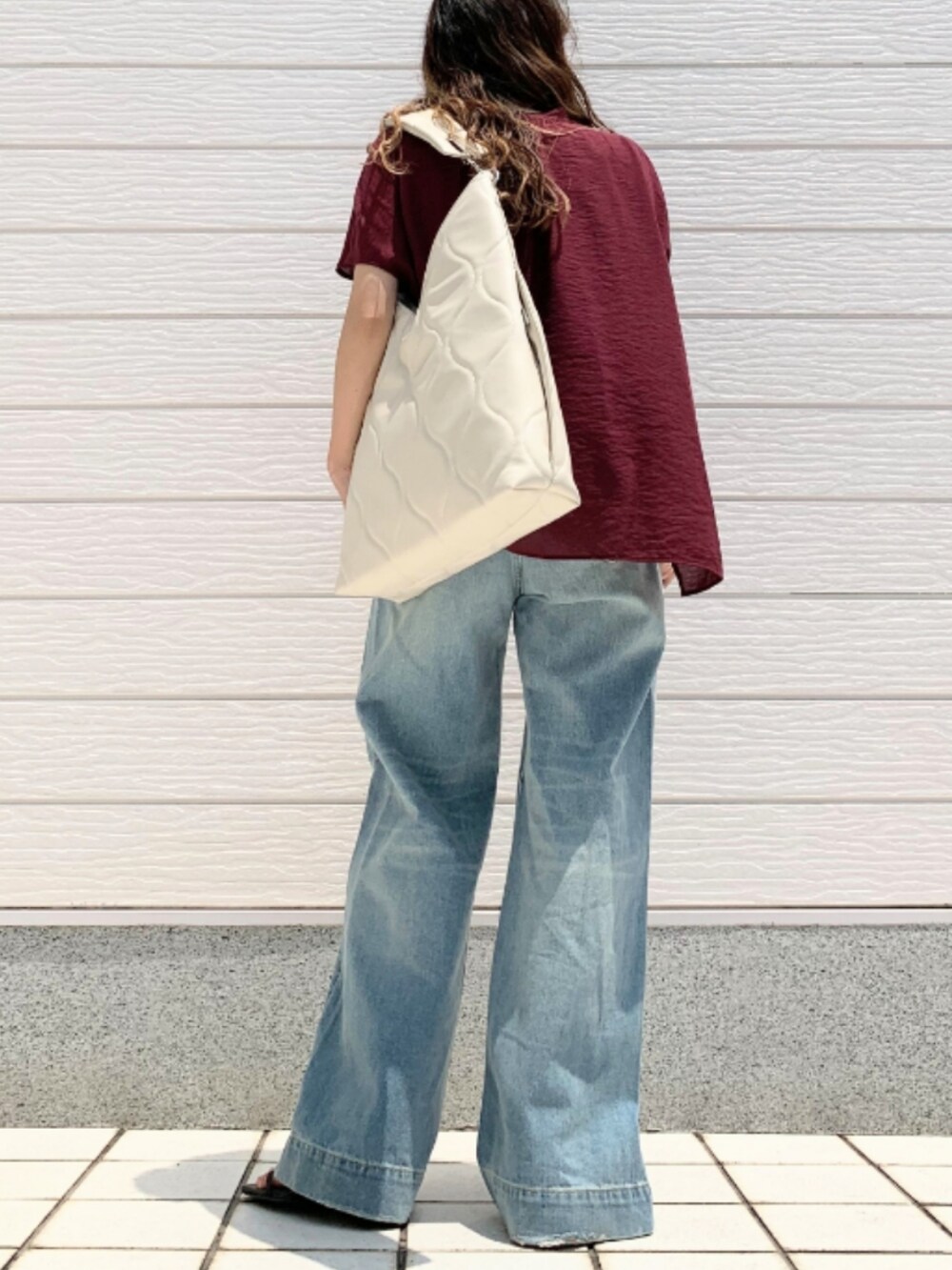 ブルー系のデニムパンツ、レッド系のシャツ/ブラウス、ホワイト系のハンドバッグを着用したレディースの夏コーディネートの3枚目の写真