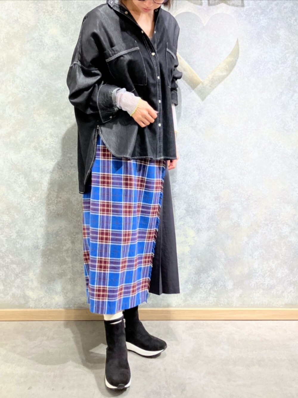 グレー系のブーツ、ブルー系のスカート、グレー系のTシャツ/カットソーを着用したレディースの秋コーディネートの2枚目の写真