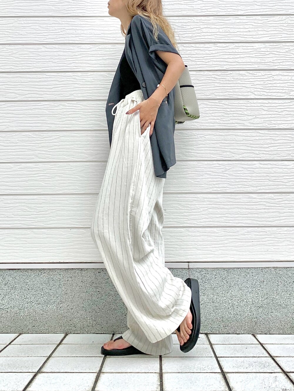 グレー系のトートバッグ、グレー系のテーラードジャケット、ホワイト系のその他パンツを着用したレディースの夏コーディネートの2枚目の写真