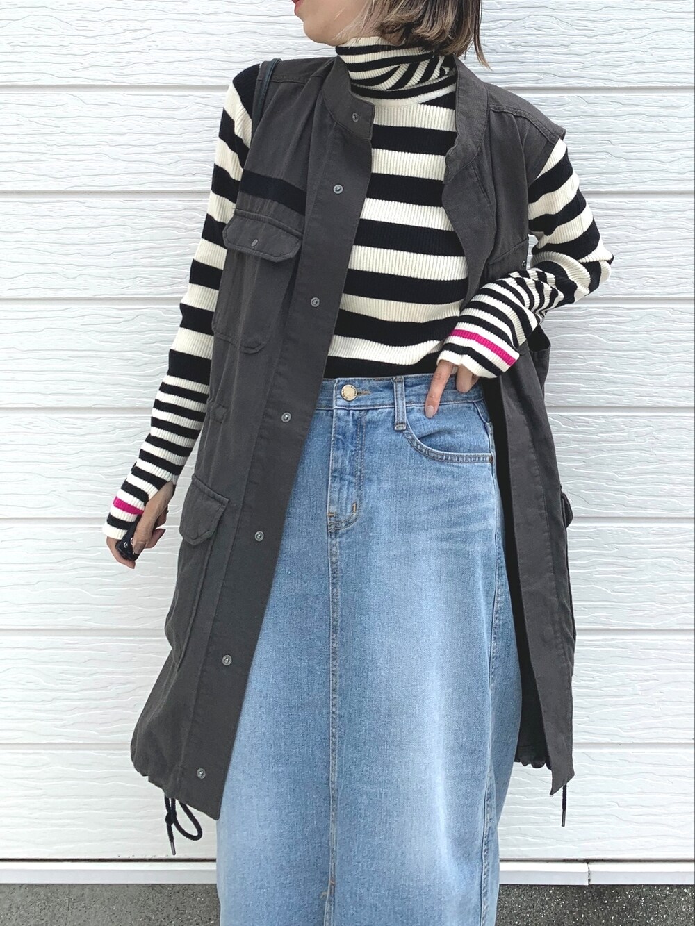 ブラック系のベスト、ホワイト系のニット/セーター、ブルー系のデニムスカートを着用したレディースの夏コーディネートの3枚目の写真