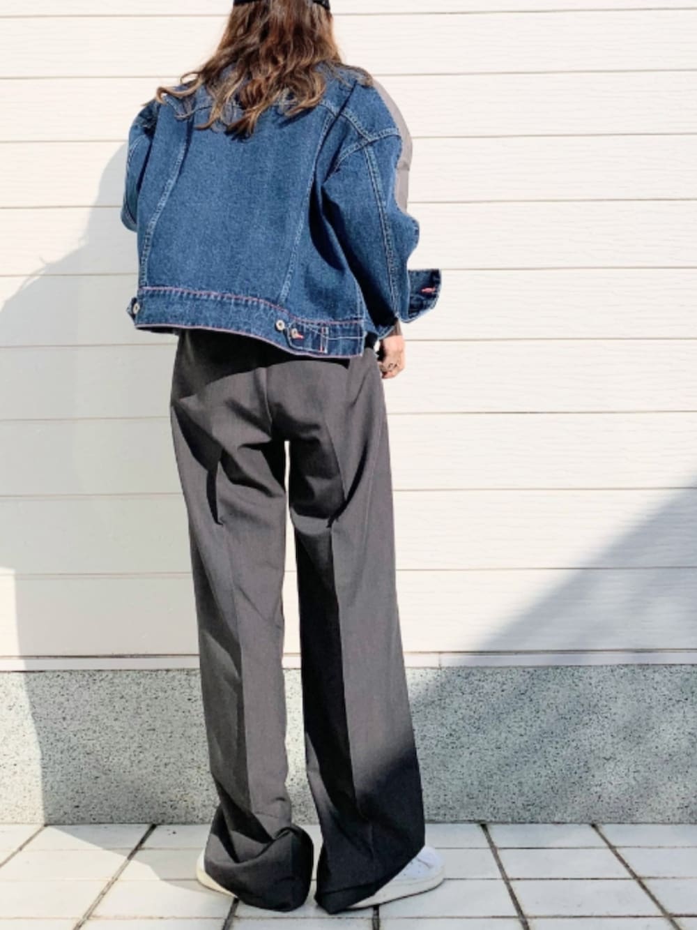 グレー系のスラックス、ブルー系のデニムジャケット、ブラック系のキャミソールを着用したレディースの冬コーディネートの2枚目の写真