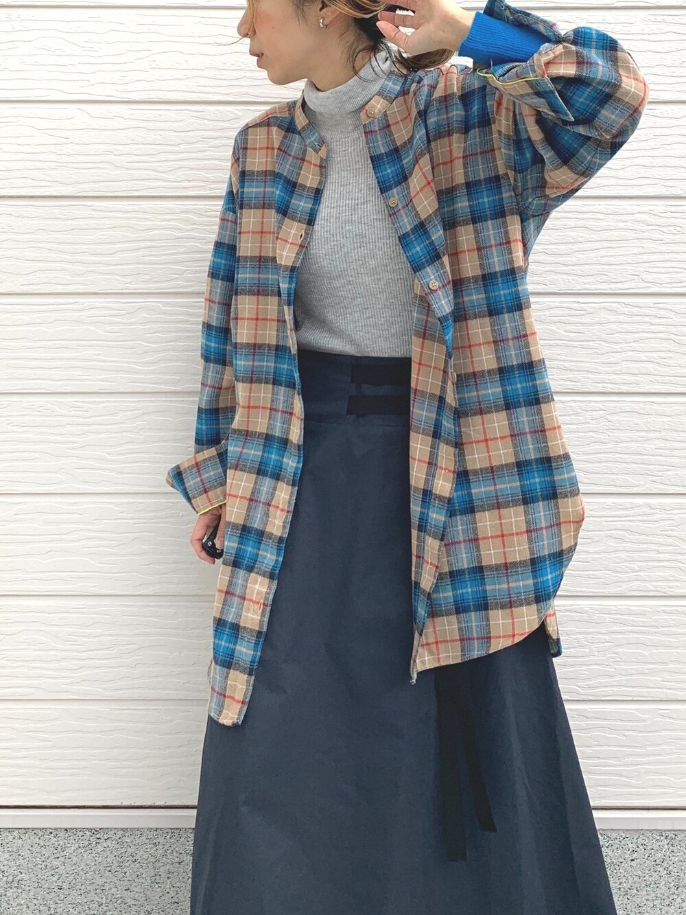 ブルー系のスカート、グレー系のニット/セーター、シルバー系のスニーカーを着用したレディースの冬コーディネートの3枚目の写真