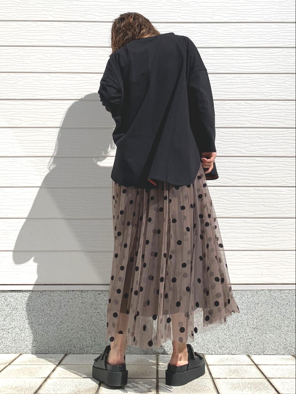 ブラック系のTシャツ/カットソー、ブラウン系のスカート、ブラック系のサンダルを着用したレディースの春コーディネートの3枚目の写真