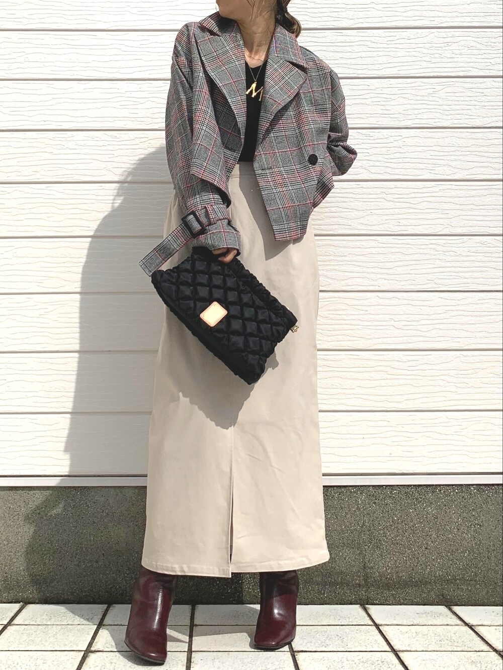 ブラック系のトレンチコート、ブラック系のショルダーバッグ、ブラウン系のブーツを着用したレディースの秋コーディネートの3枚目の写真