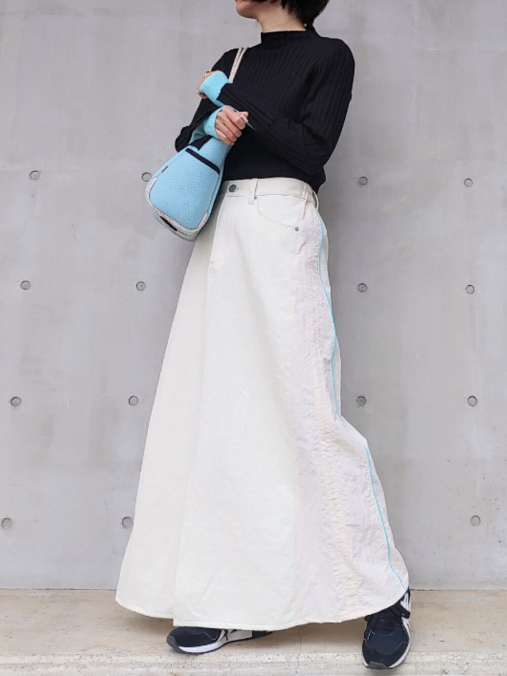 ブルー系のトートバッグ、ホワイト系のデニムスカート、ブラック系のスニーカーを着用したレディースの冬コーディネートの2枚目の写真