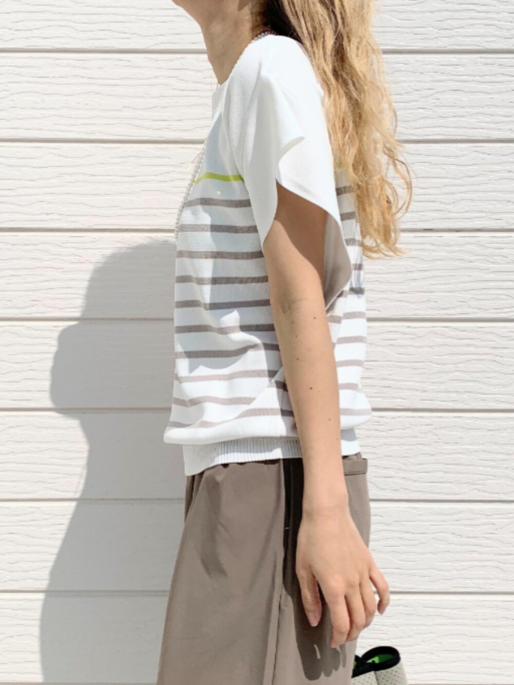 グレー系のその他パンツ、グレー系のトートバッグ、ホワイト系のニット/セーターを着用したレディースの春コーディネートの4枚目の写真