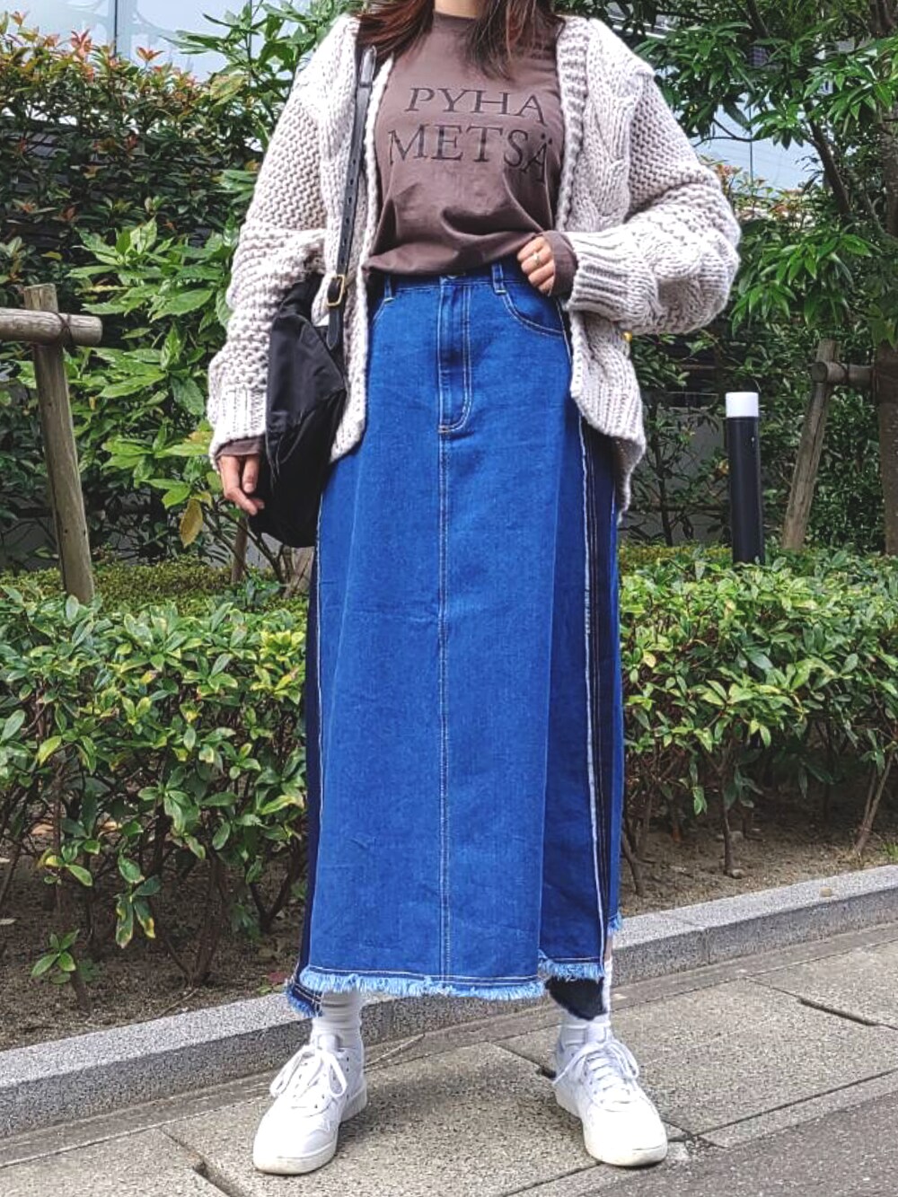 グレー系のTシャツ/カットソー、ブルー系のデニムスカート、ホワイト系のスニーカーを着用したレディースの秋コーディネートの2枚目の写真