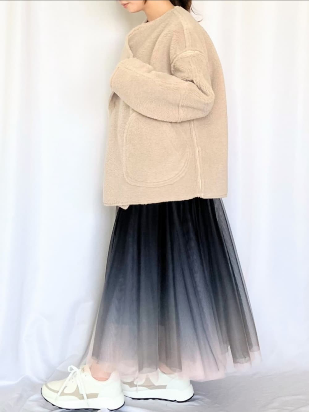 ブラック系のスカート、ホワイト系のスニーカー、ベージュ系のブルゾンを着用したレディースの冬コーディネートの3枚目の写真