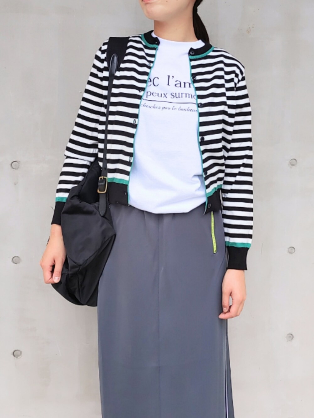 グレー系のスカート、ブラック系のカーディガン/ボレロ、ホワイト系のTシャツ/カットソーを着用したレディースの秋コーディネートの3枚目の写真