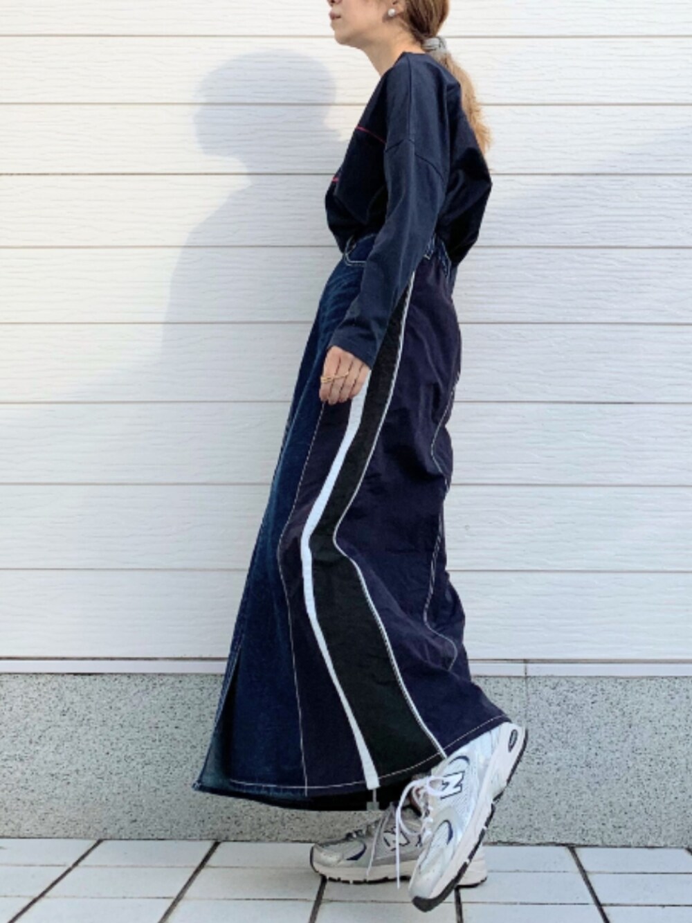 シルバー系のスニーカー、ブルー系のデニムスカート、ブルー系のTシャツ/カットソーを着用したレディースの冬コーディネートの2枚目の写真