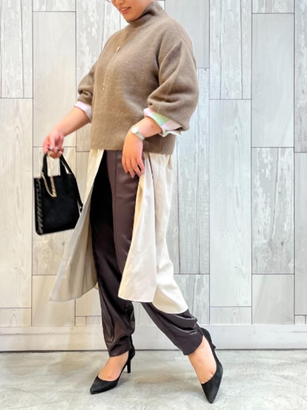 ブラウン系のニット/セーター、ブラック系のショルダーバッグ、ベージュ系のシャツワンピースを着用したレディースの冬コーディネートの2枚目の写真