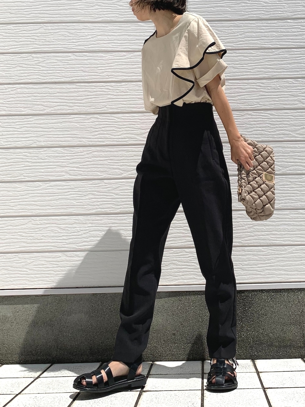 ブラック系のパンツ、ベージュ系のショルダーバッグ、ブラック系のサンダルを着用したレディースの夏コーディネートの2枚目の写真