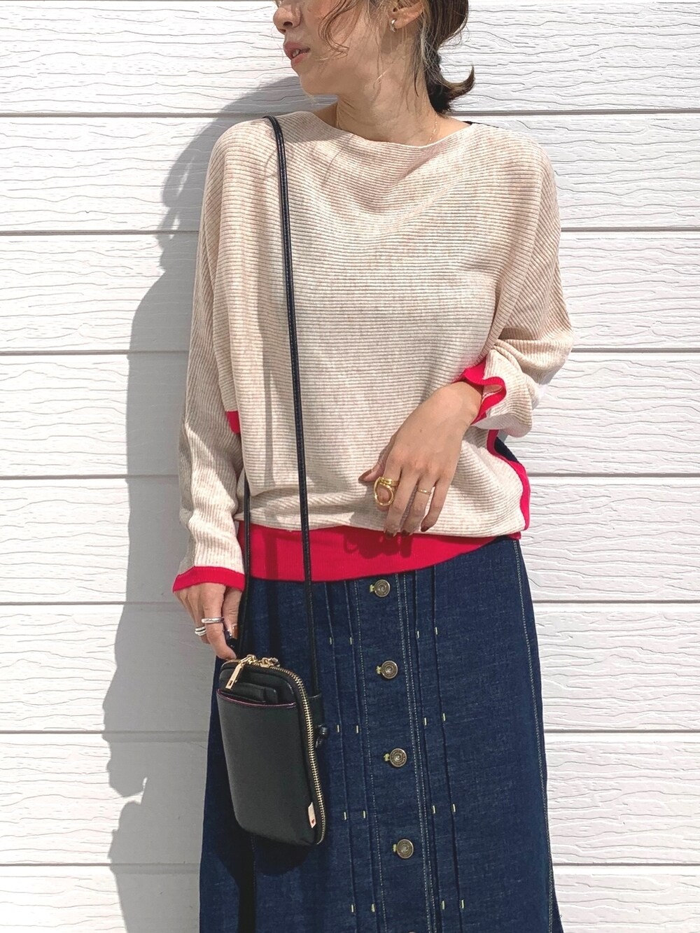 ブルー系のデニムスカート、ブラック系のスニーカー、ブラック系のショルダーバッグを着用したレディースの秋コーディネートの4枚目の写真