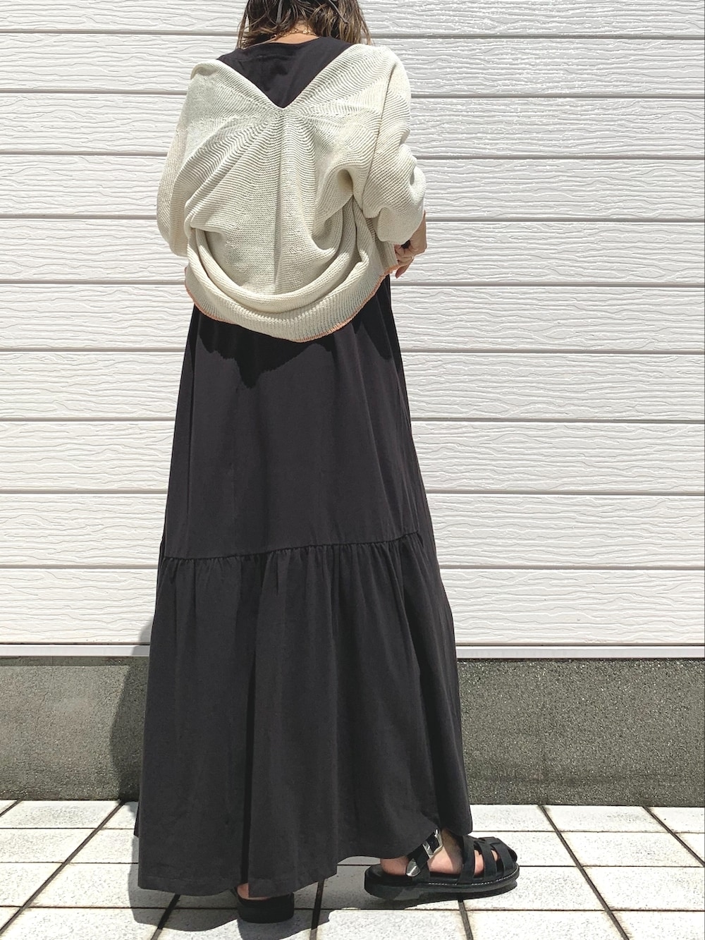 ブラック系のサンダル、ホワイト系のカーディガン/ボレロ、ブラック系のワンピースを着用したレディースの夏コーディネートの2枚目の写真