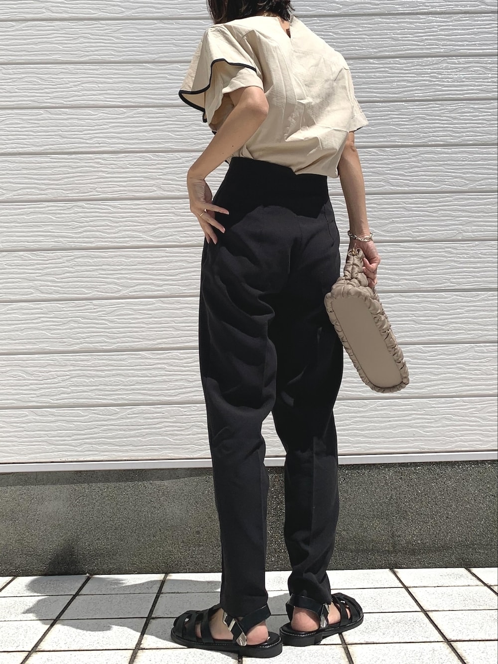 ブラック系のパンツ、ベージュ系のショルダーバッグ、ブラック系のサンダルを着用したレディースの夏コーディネートの3枚目の写真
