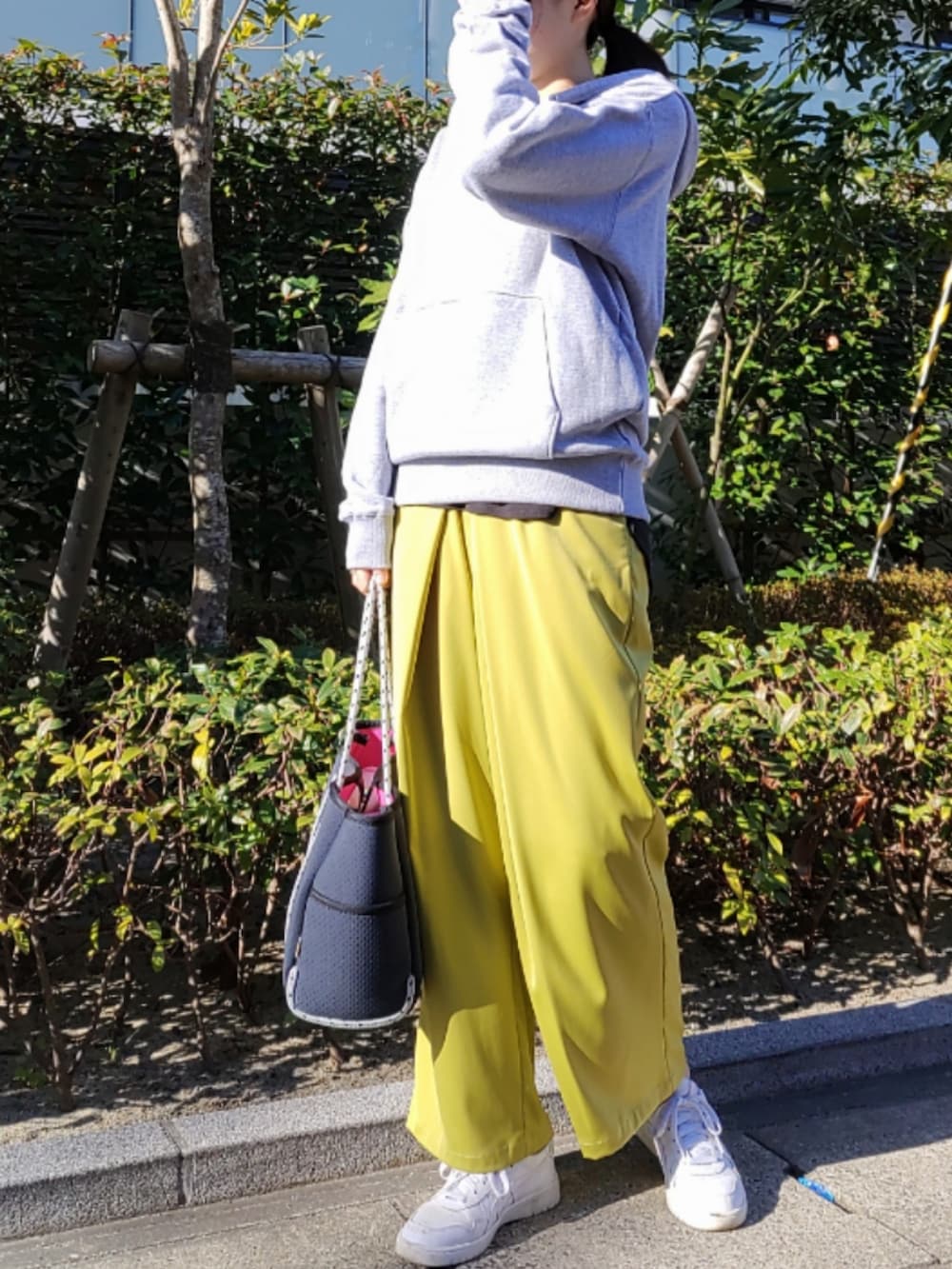 ブルー系のトートバッグ、グリーン系のスラックス、ホワイト系のスニーカーを着用したレディースの冬コーディネートの2枚目の写真