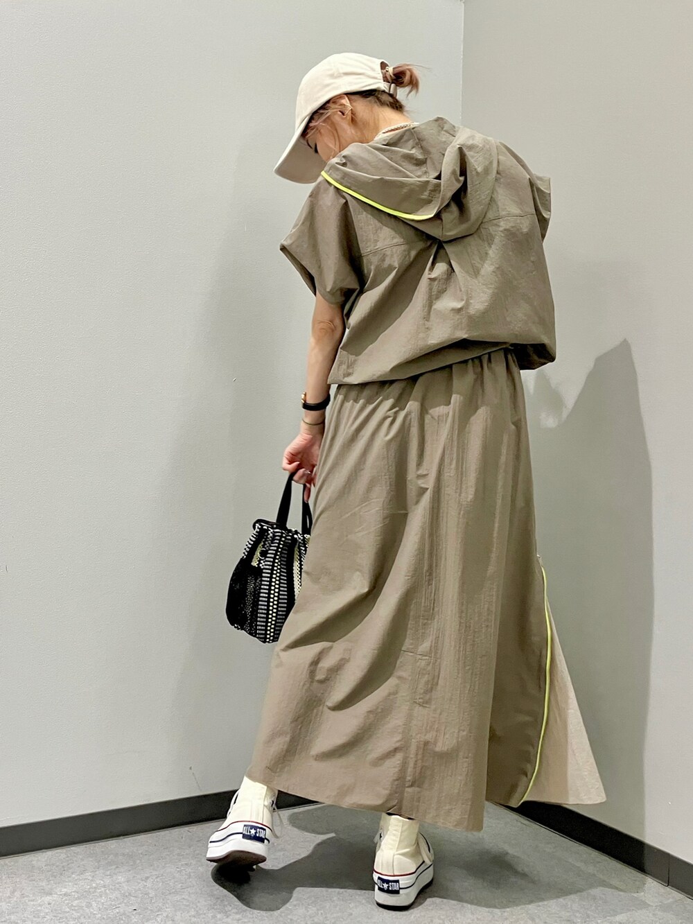 グリーン系のパーカー、グリーン系のスカート、ブラック系のトートバッグを着用したレディースの夏コーディネートの3枚目の写真