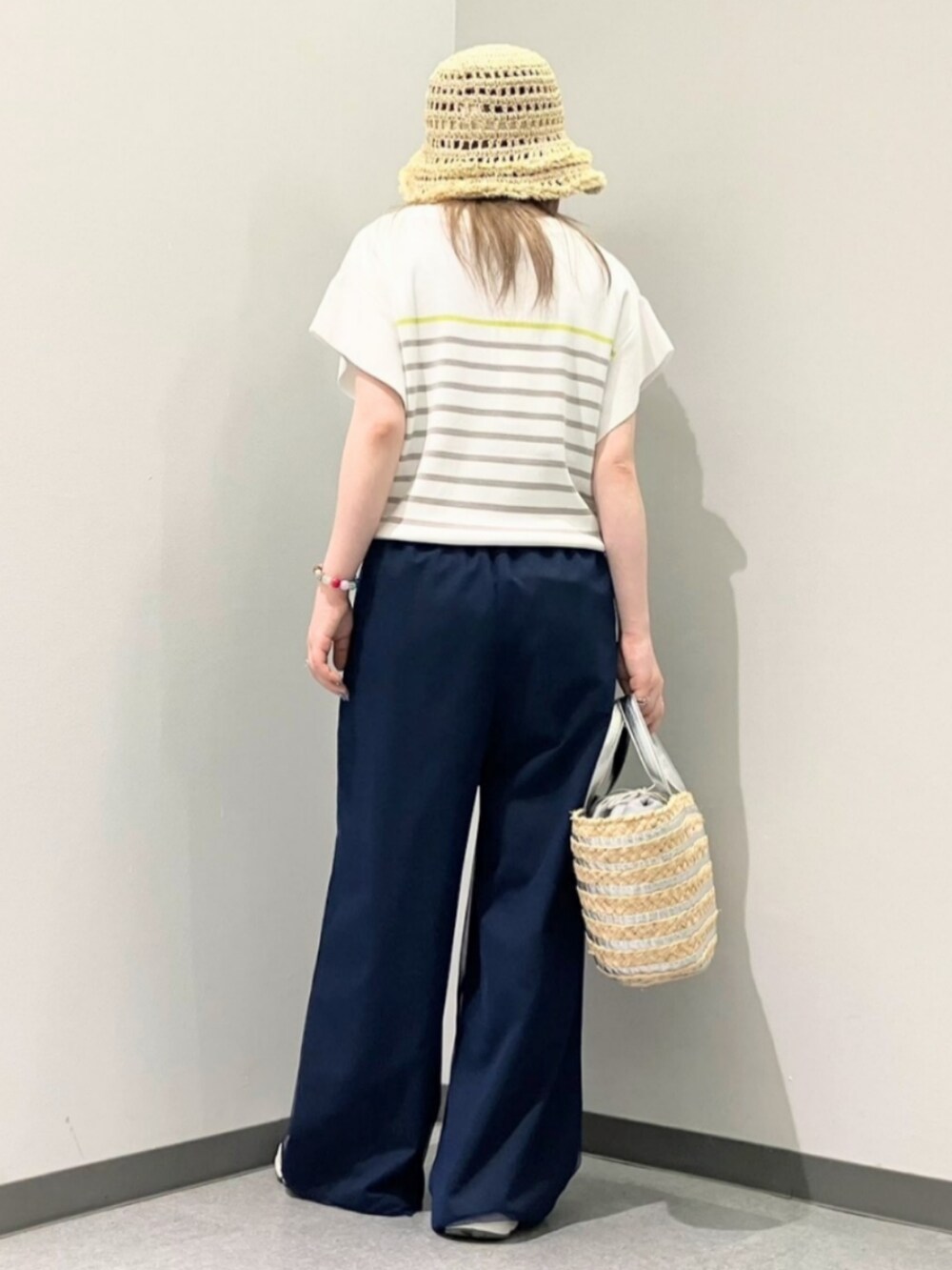 ブルー系のその他パンツ、ホワイト系のニット/セーター、シルバー系のかごバッグを着用したレディースの春コーディネートの3枚目の写真