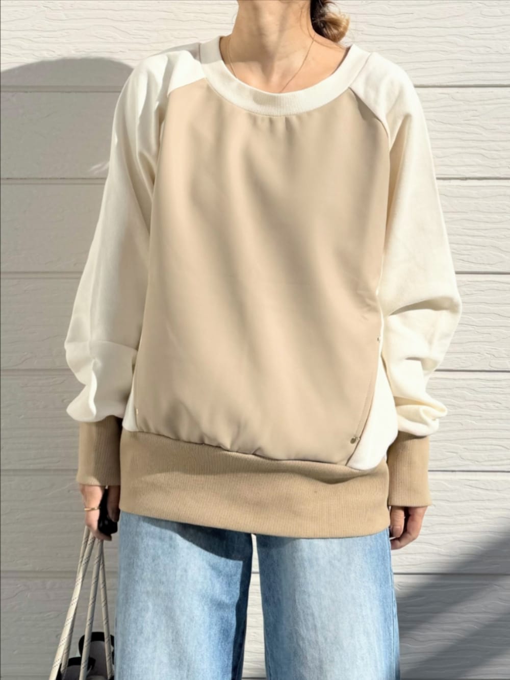 ブルー系のトートバッグ、ブルー系のデニムパンツ、ベージュ系のスウェットを着用したレディースの冬コーディネートの3枚目の写真