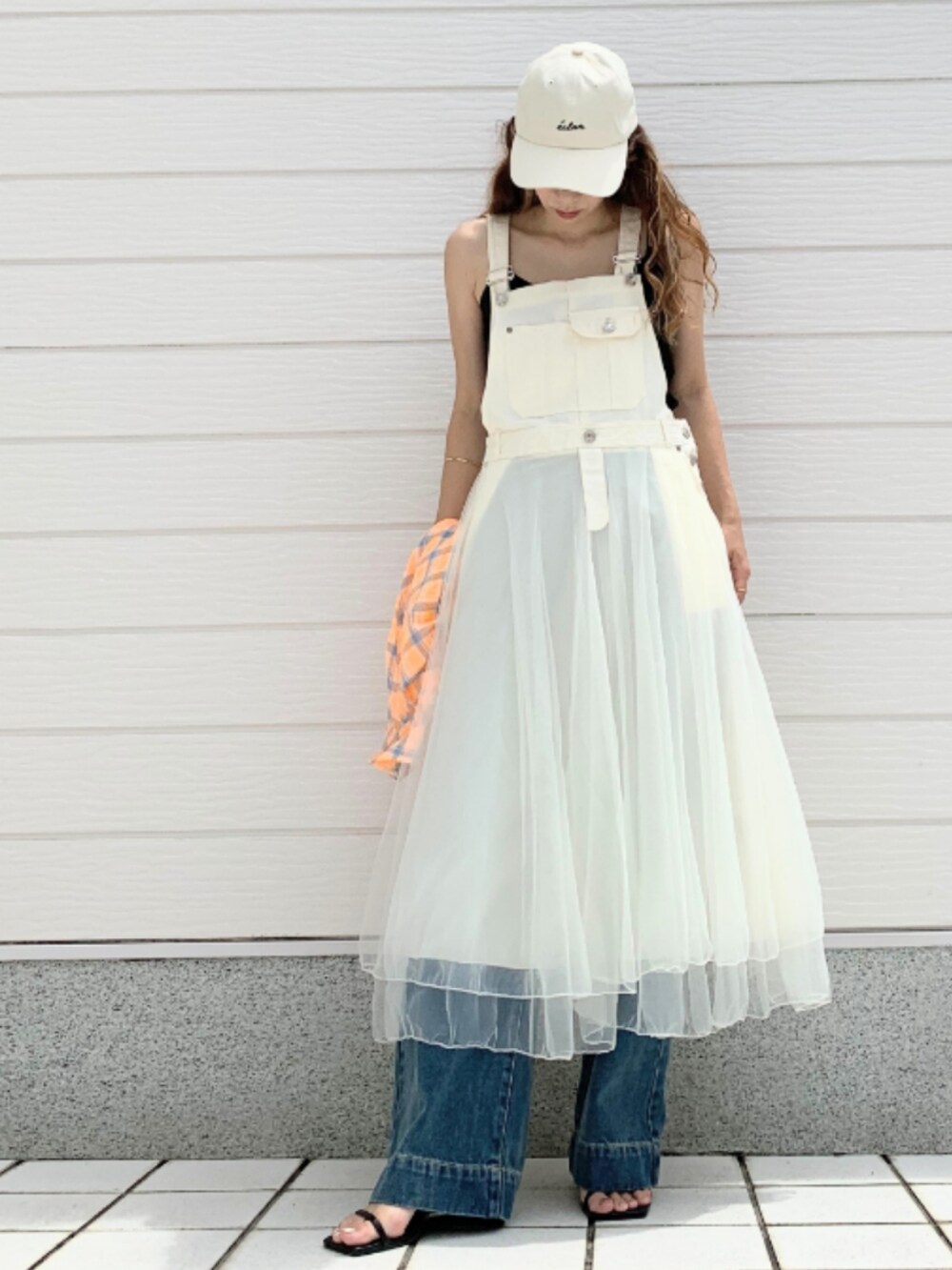 ブルー系のデニムパンツ、ブラック系のタンクトップ、ホワイト系のジャンパースカートを着用したレディースの夏コーディネートの2枚目の写真