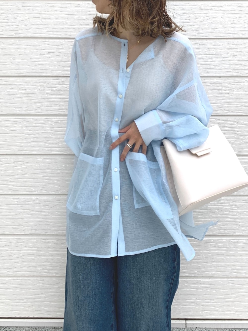 ブルー系のデニムパンツ、ブラック系のサンダル、ホワイト系のハンドバッグを着用したレディースの春コーディネートの5枚目の写真