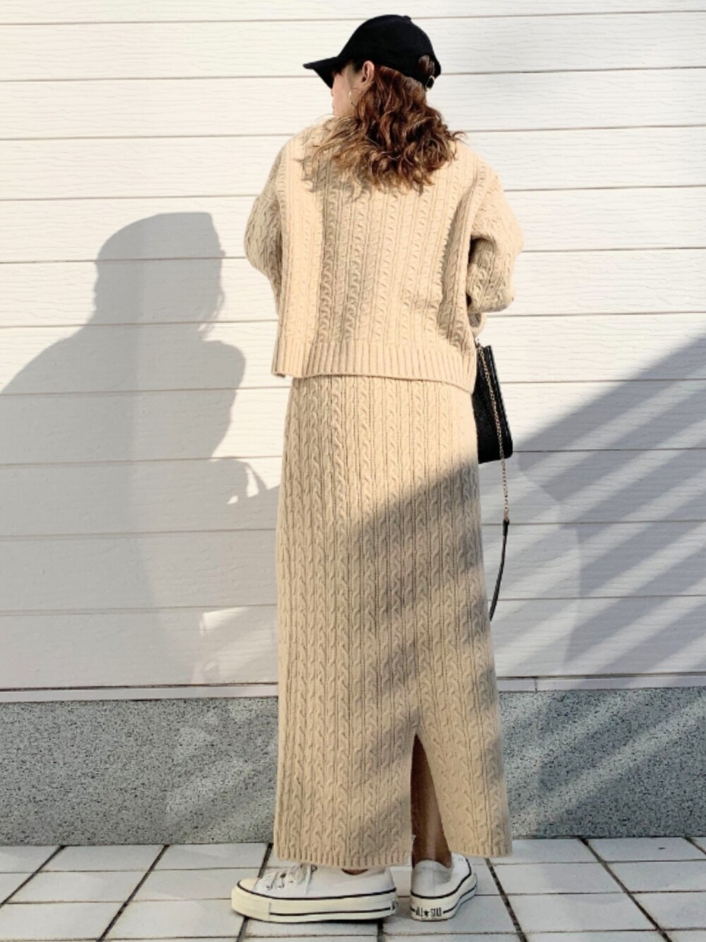 ブラック系のショルダーバッグ、ホワイト系のスニーカー、ベージュ系のニット/セーターを着用したレディースの冬コーディネートの3枚目の写真