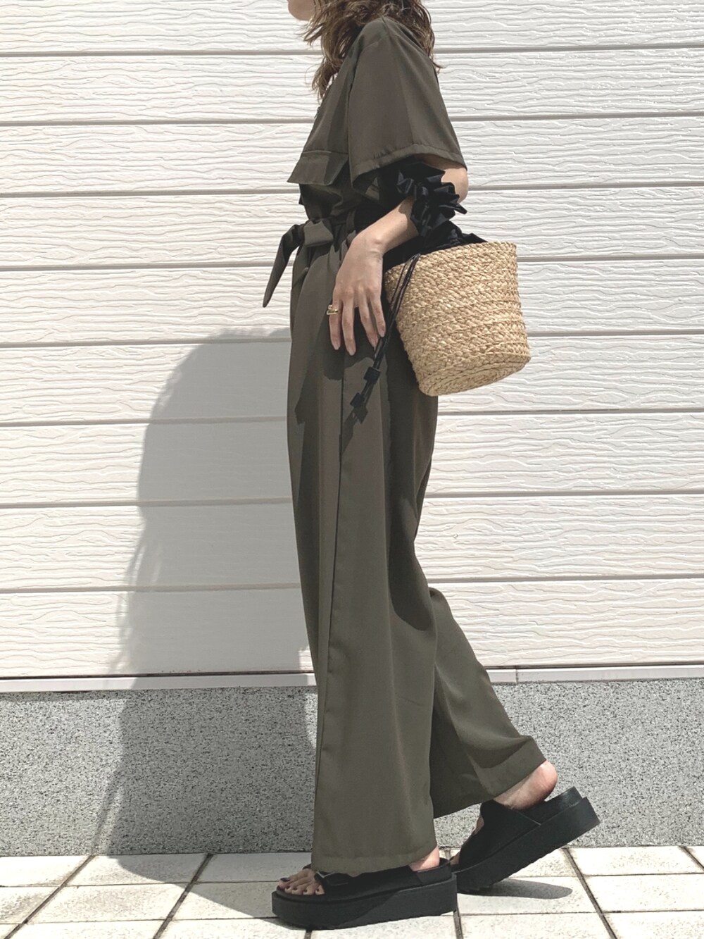 ブラック系のかごバッグ、グリーン系のつなぎ/オールインワン、ブラック系のサンダルを着用したレディースの春コーディネートの2枚目の写真