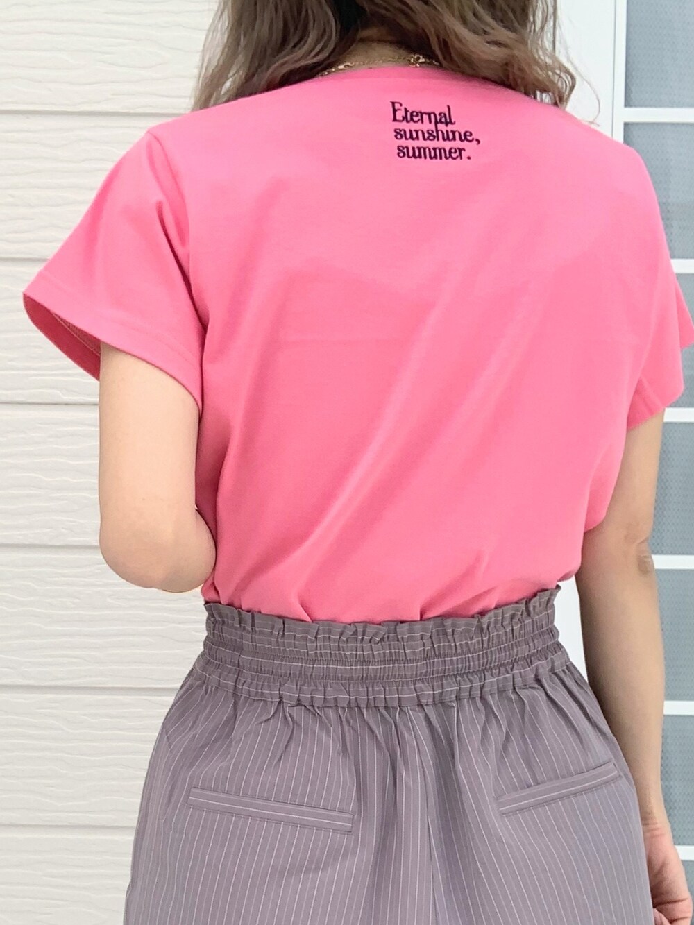 ピンク系のTシャツ/カットソー、グレー系のスラックス、ホワイト系のキャップを着用したレディースの春コーディネートの5枚目の写真