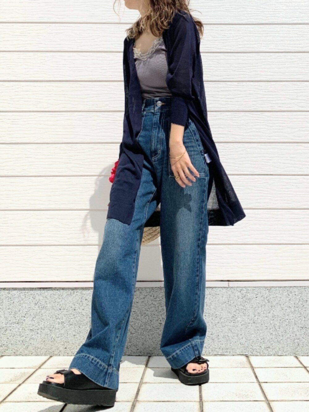 ブラック系のサンダル、ブルー系のデニムパンツ、ピンク系のかごバッグを着用したレディースの春コーディネートの2枚目の写真