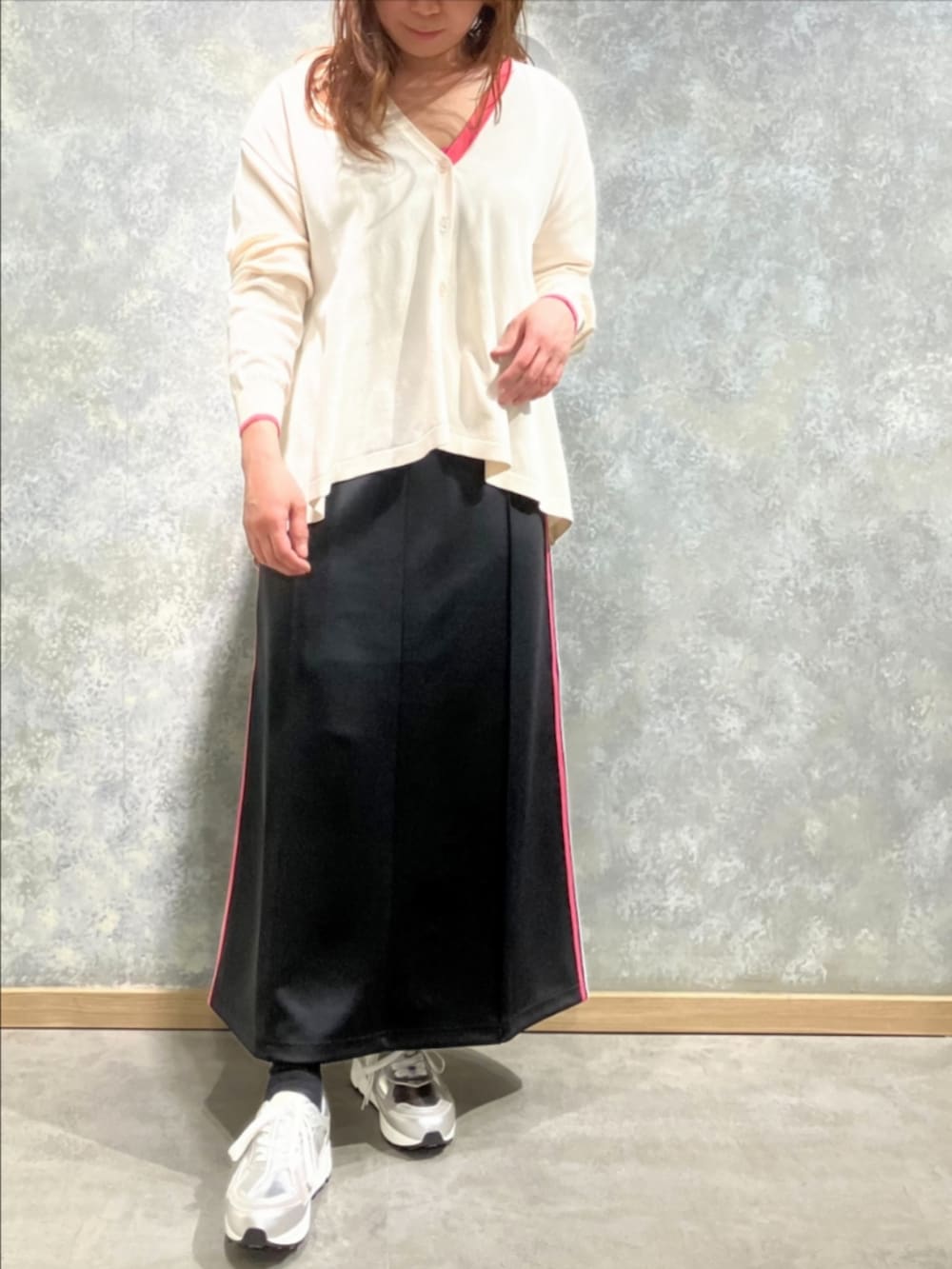 シルバー系のスニーカー、ベージュ系のカーディガン/ボレロ、ブラック系のスカートを着用したレディースの冬コーディネートの2枚目の写真