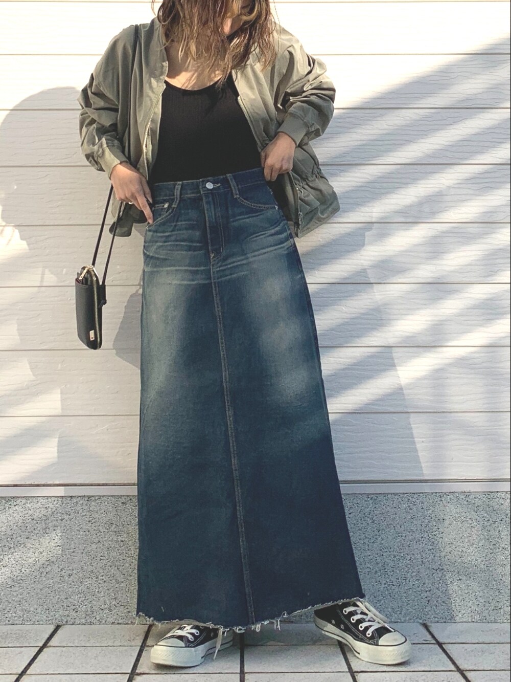 ブラック系のキャミソール、ブルー系のデニムスカート、ブラック系のスニーカーを着用したレディースの冬コーディネートの2枚目の写真