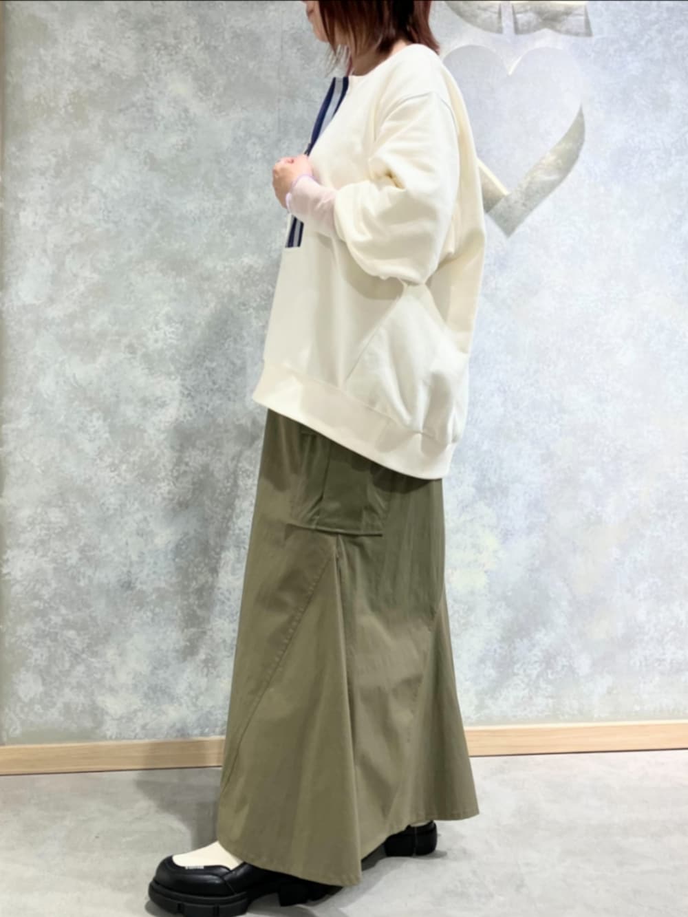 グリーン系のスカート、ホワイト系のスウェット、ホワイト系のブーツを着用したレディースの秋コーディネートの3枚目の写真